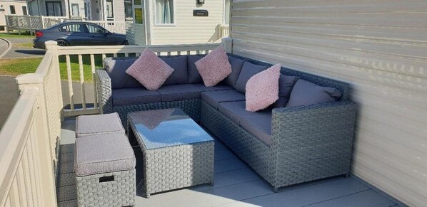 Un canapé modulable avec des coussins, une petite table et des poufs sur une terrasse couverte.