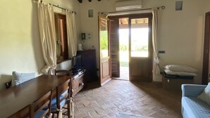 A cozy room with a wooden table, chairs, a TV, and a sofa. There's a door leading to an outdoor area. - Beautiful villa in the park of Elba Island (Redinoce)
