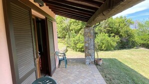 A covered patio with a stone pillar, a door, and a chair. - Beautiful villa in the park of Elba Island (Redinoce)