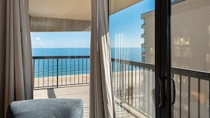 Un balcon avec vue sur la mer et un bâtiment en arrière-plan.