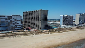 Un hôtel en bord de mer, composé de plusieurs immeubles de grande hauteur, avec une plage de sable et une vue sur l’océan.