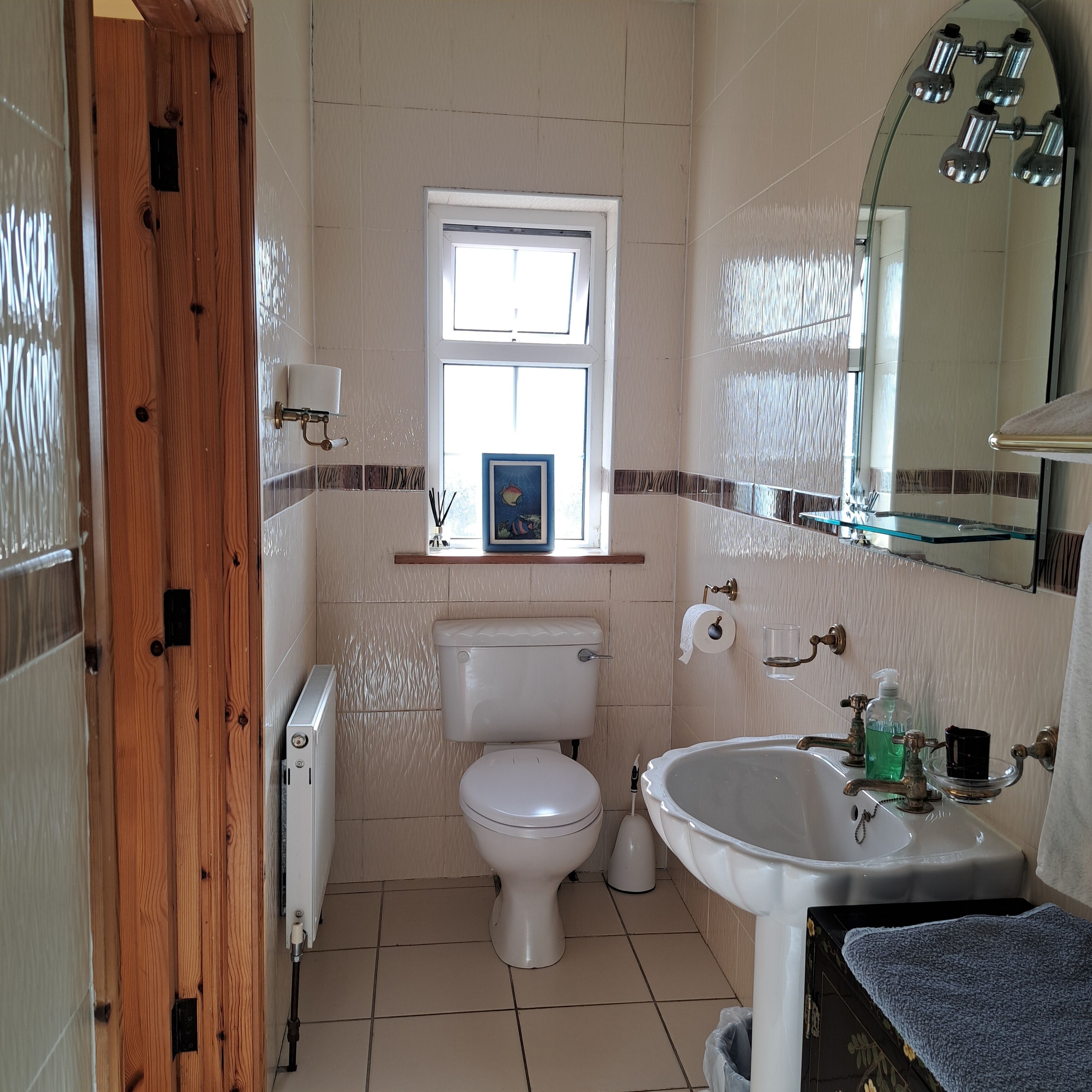 A bathroom with a toilet, sink, and a window.
