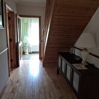 En hall med trägolv och ett sluttande tak. Där finns ett skåp med en lampa på och en skylt på golvet.