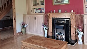 A living room with a wooden coffee table, a fireplace, and a staircase leading to another room. - Spacious 6-bed House 10 Minutes From Knock Airport (Kilmovee)