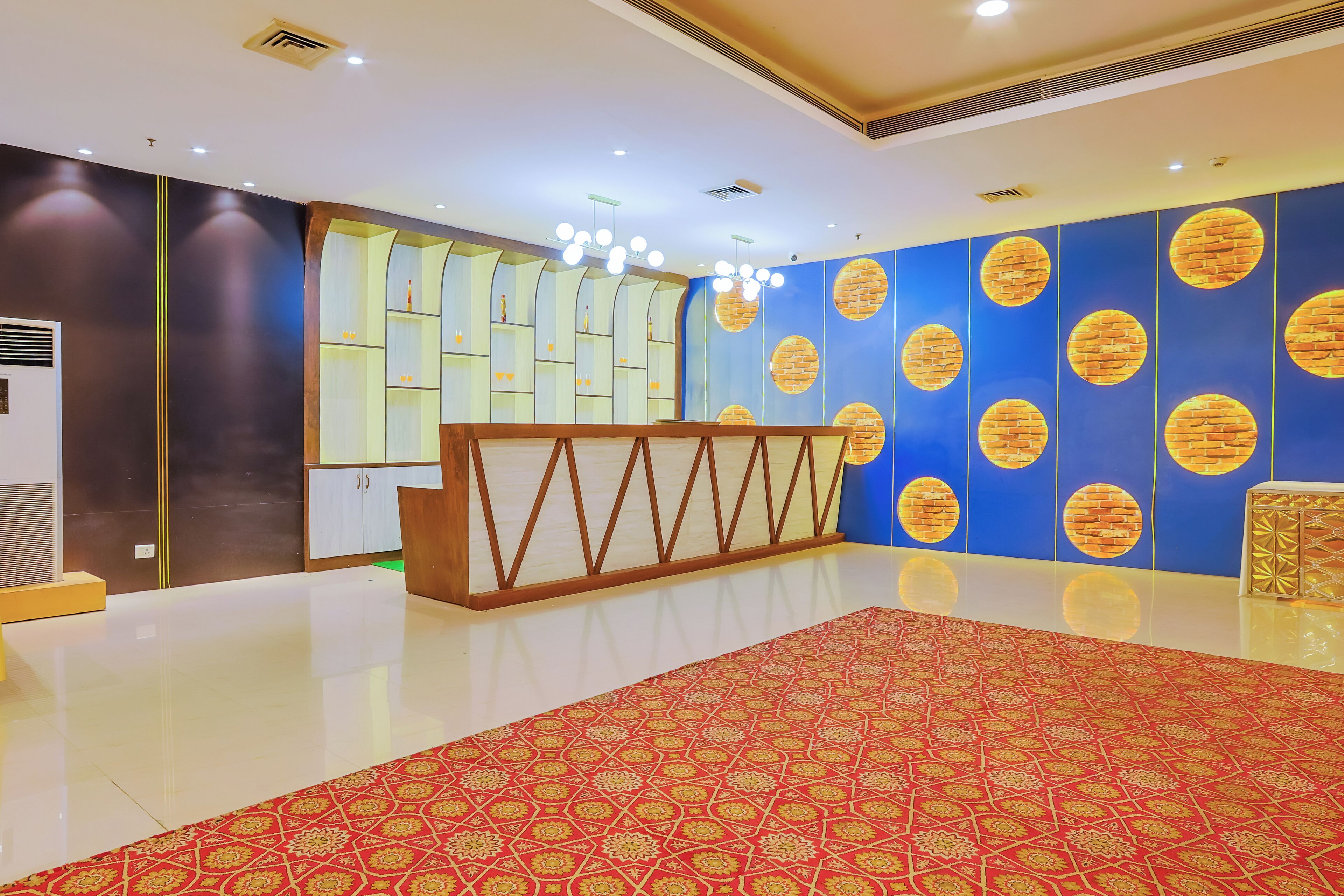 A hotel lobby with a reception desk, a red patterned carpet, and blue walls with circular designs.