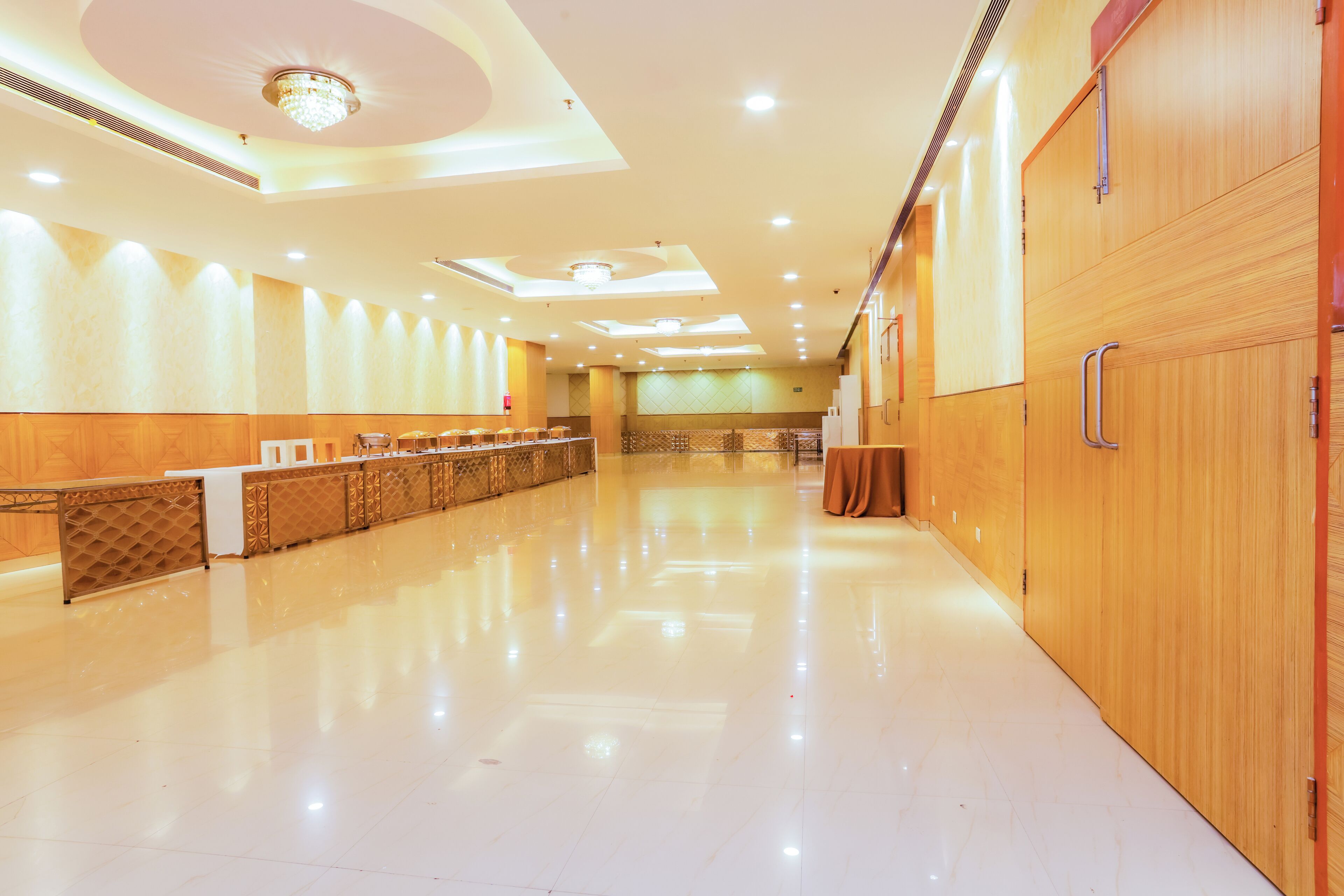 A spacious hotel lobby with a reception desk, wooden paneling, and a polished floor.