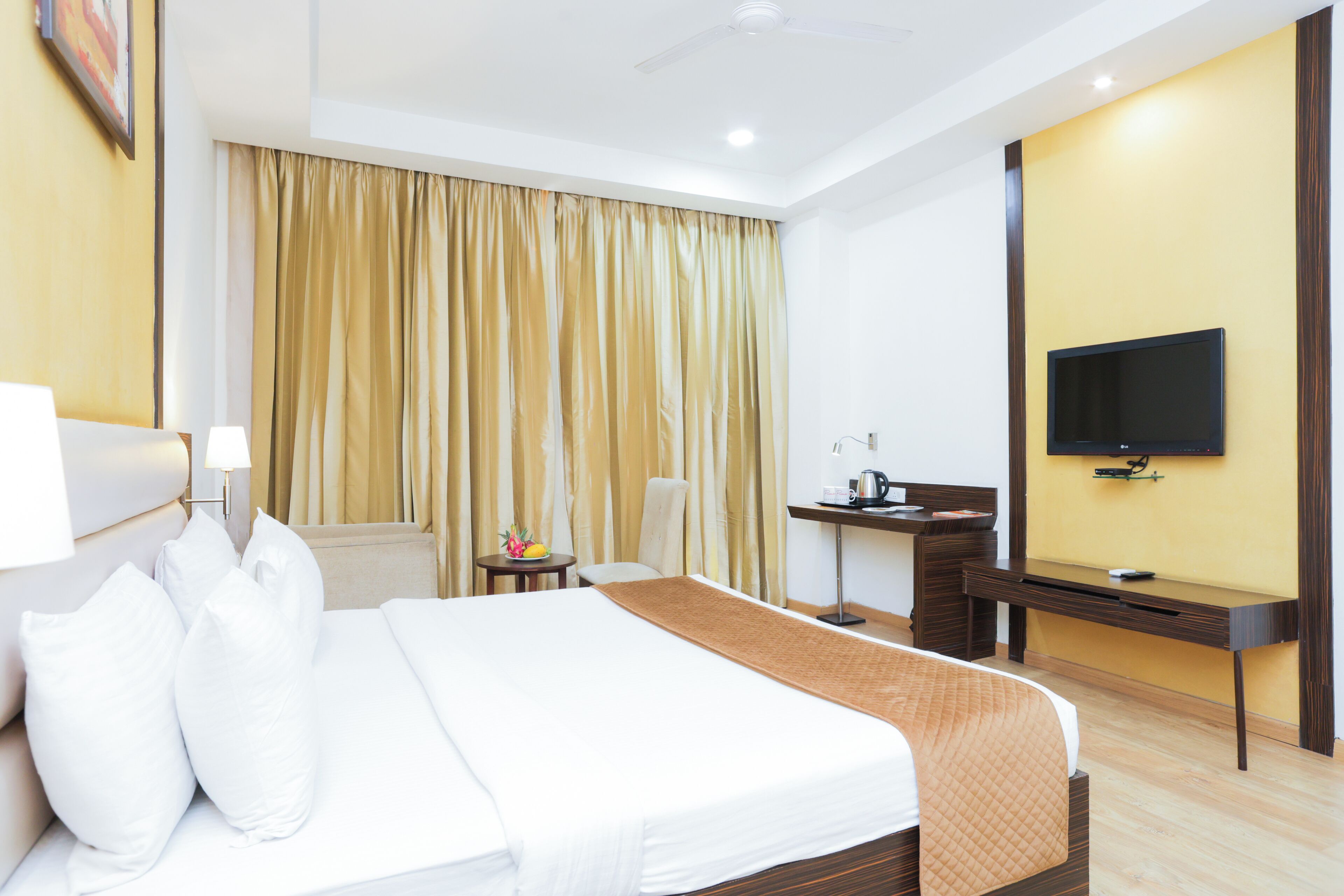 A hotel room with a bed, a desk, a chair, a television, and a window with curtains.