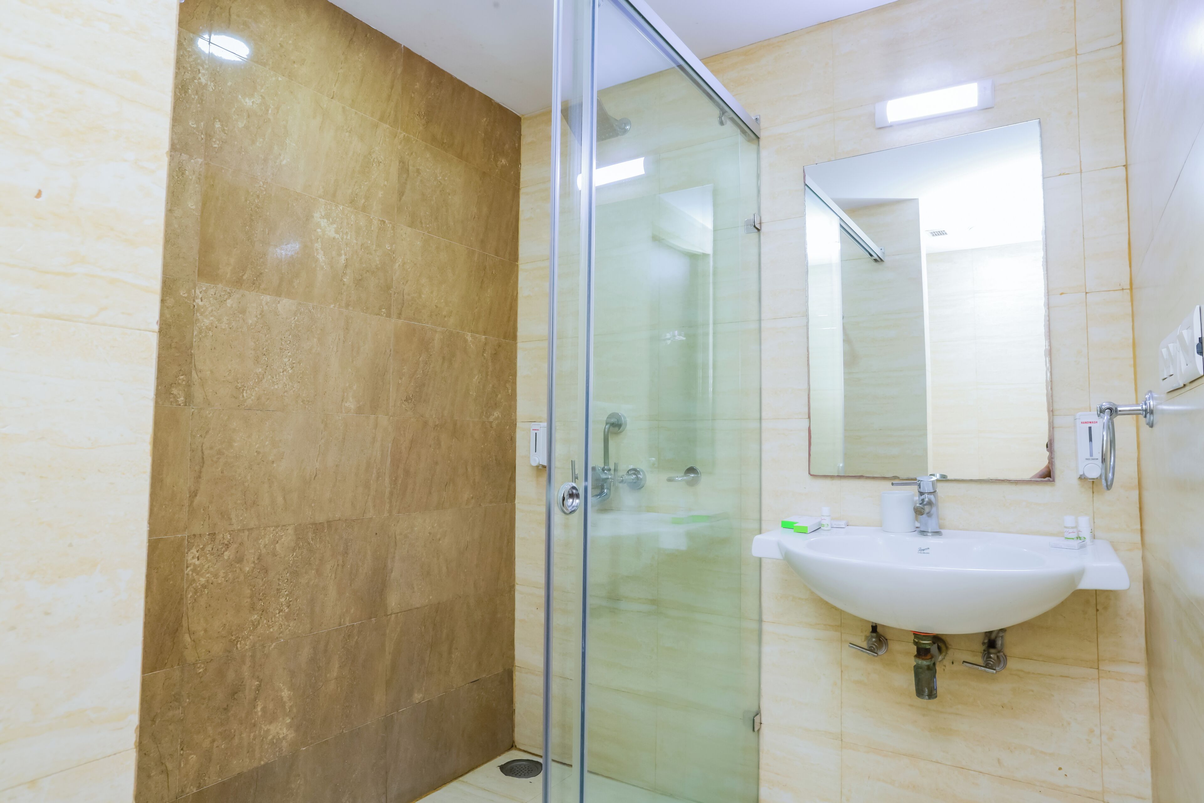 A bathroom with a glass shower enclosure, a sink, and a mirror.
