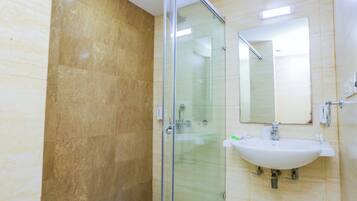 A bathroom with a glass shower enclosure, a sink, and a mirror.