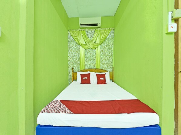 A single bed with a white and red bedspread, two red pillows with "OYO" text, and a green curtain. - OYO 90454 Haza Harmoni Guesthouse (Kota Bharu)