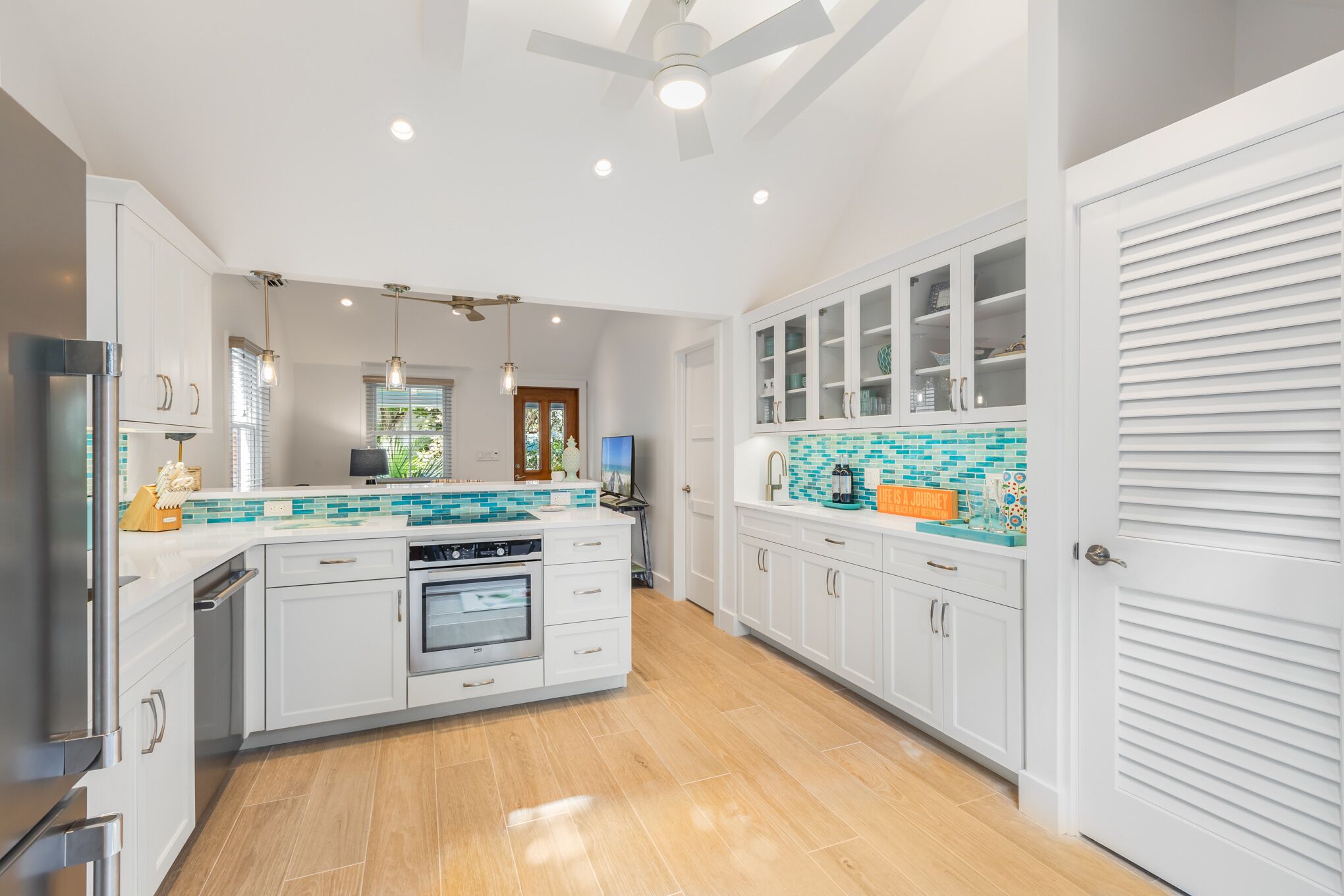 A modern kitchen with white cabinetry, a central island, and a tiled backsplash.