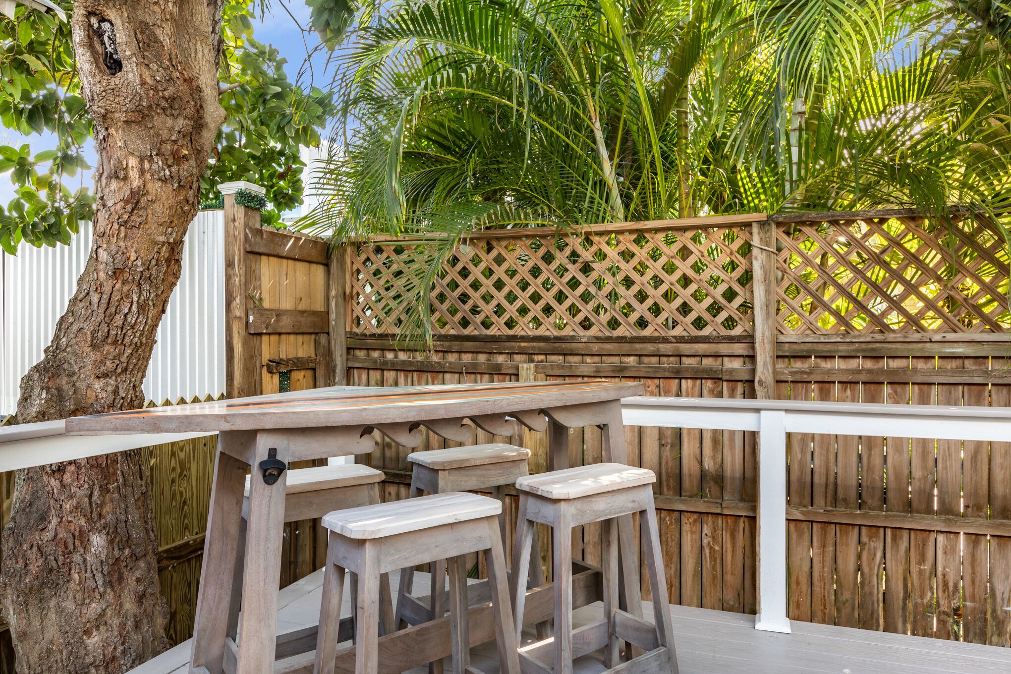 An outdoor deck with wooden furniture and a lattice fence.