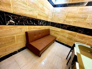 A corner room with a brown leather sofa, wooden walls, and a marble accent wall. - Smart Apartments (Lahore)