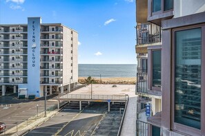A multi-story hotel with a prominent 'FLYING CLOUD' sign, a parking area, and a view of the beach and ocean. - 9400 Building - Ocean Views in this 2 Bedroom with Outdoor Pool! (Ocean City)
