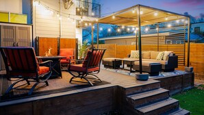 An outdoor patio area with a wooden deck, seating arrangements, and string lights. - Wow! 5-Star Luxury ~ Safe & 3M to DT ~ (Austin)
