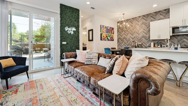 A modern living room with a leather sofa, a coffee table, and a patterned rug. - Wow! 5-Star Luxury ~ Safe & 3M to DT ~ (Austin)