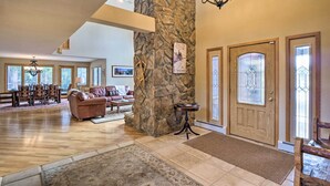 A spacious living room with a stone pillar, a fireplace, and a large dining area with a chandelier. - Grand Fraser Escape w/ Private Deck & Hot Tub (Fraser)