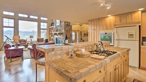 A spacious kitchen with a large island, wooden cabinets, and a stone backsplash. - Grand Fraser Escape w/ Private Deck & Hot Tub (Fraser)