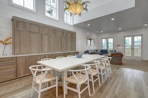 A spacious kitchen with a large island, white cabinetry, and a dining area with white chairs. - Overlook Grassy Dune Near Dune Pool@Cinnamon Shore+More Great Amenities (Port Aransas)