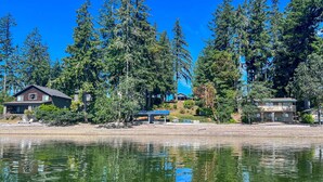 Une propriété située au bord d’un lac, comprenant une maison, un patio couvert et de grands arbres.