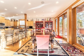 A modern kitchen with wooden cabinets, a central island, and a dining area with a large table and chairs.