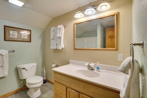 A bathroom with a toilet, sink, and mirror. There are towels hanging on the wall and a picture frame. - Sturgis Rally Home Base for Riders & Couples! (Lead)