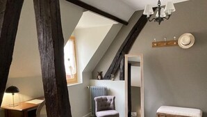 A cozy attic bedroom with exposed wooden beams, a sloped ceiling, a large mirror, a bench, and a small table with a lamp. - La maison de Triboulet, bed and breakfast, Nutrisco, Nutrisco (Pocé-sur-Cisse)