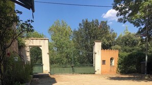 A gated area with a dirt path leading to a building with a small window and a door.