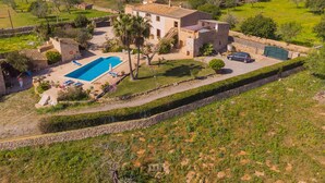 A villa with a swimming pool, a carport, and a stone wall. - Tanca - Typical Finca with Private Pool, Sleeps 8, A/C, Wi-Fi, Near Cala d'Or (Santanyí)