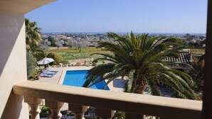 A balcony with a view of a swimming pool, palm trees, and a distant landscape. - Tanca - Typical Finca with Private Pool, Sleeps 8, A/C, Wi-Fi, Near Cala d'Or (Santanyí)