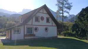 Una casa con tetto spiovente, diverse finestre e un prato curato.