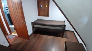 Una camera da letto con un letto, pavimento in legno, una finestra decorata con una forma a cuore e una porta che dà su un'altra stanza.