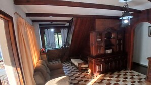 Una stanza con pavimento a scacchi, un divano, un mobiletto in legno e una scala che conduce a un balcone.
