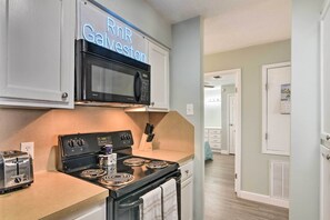 A kitchen with a microwave, stove, and toaster. There is a neon sign above the microwave that reads "RnR Galveston." - Gulf Views & Resort Perks: Walkable Galveston Gem (Galveston)