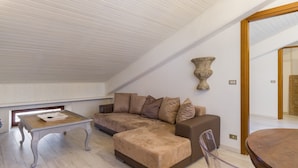 A modern living room with a wooden ceiling, a brown sectional sofa, a small wooden table, and a large vase on the wall.