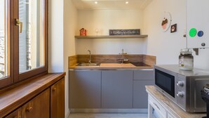 A compact kitchen with a wooden countertop, a built-in sink, and a microwave.