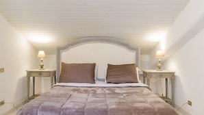 A bedroom with a large bed, two bedside tables with lamps, and a white ceiling.