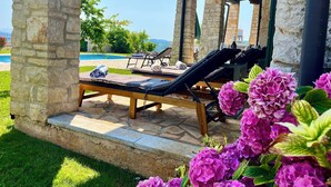 Eine Steinstützpfeiler mit Liegestühlen mit Blick auf einen Pool und eine Berglandschaft.