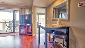 A room with a large TV, a bar area, and a sliding glass door leading to an outdoor patio.