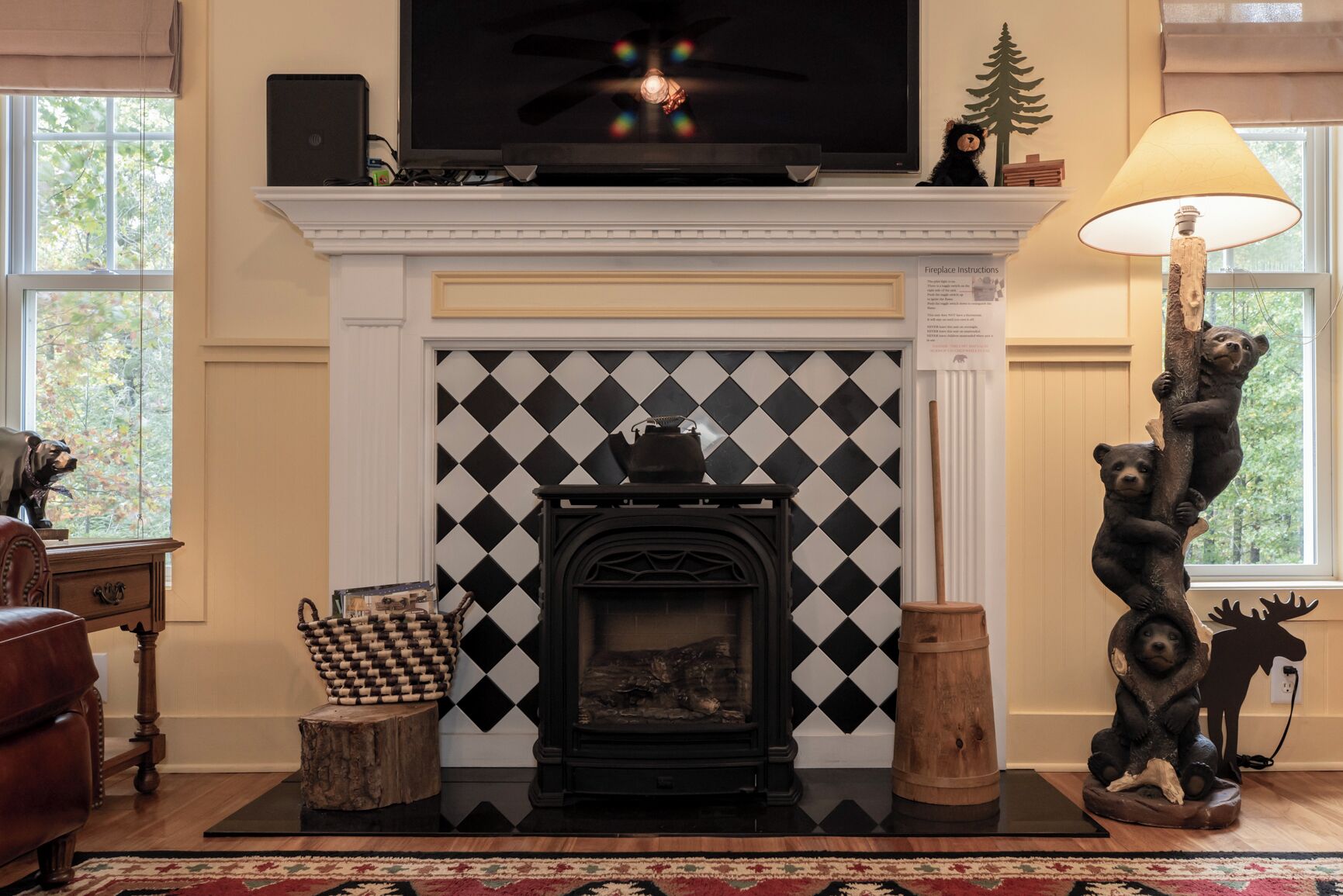 A living room with a fireplace, a television above it, and a lamp to the right.