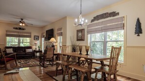 A dining area with a wooden table and chairs, a chandelier, and a fireplace.