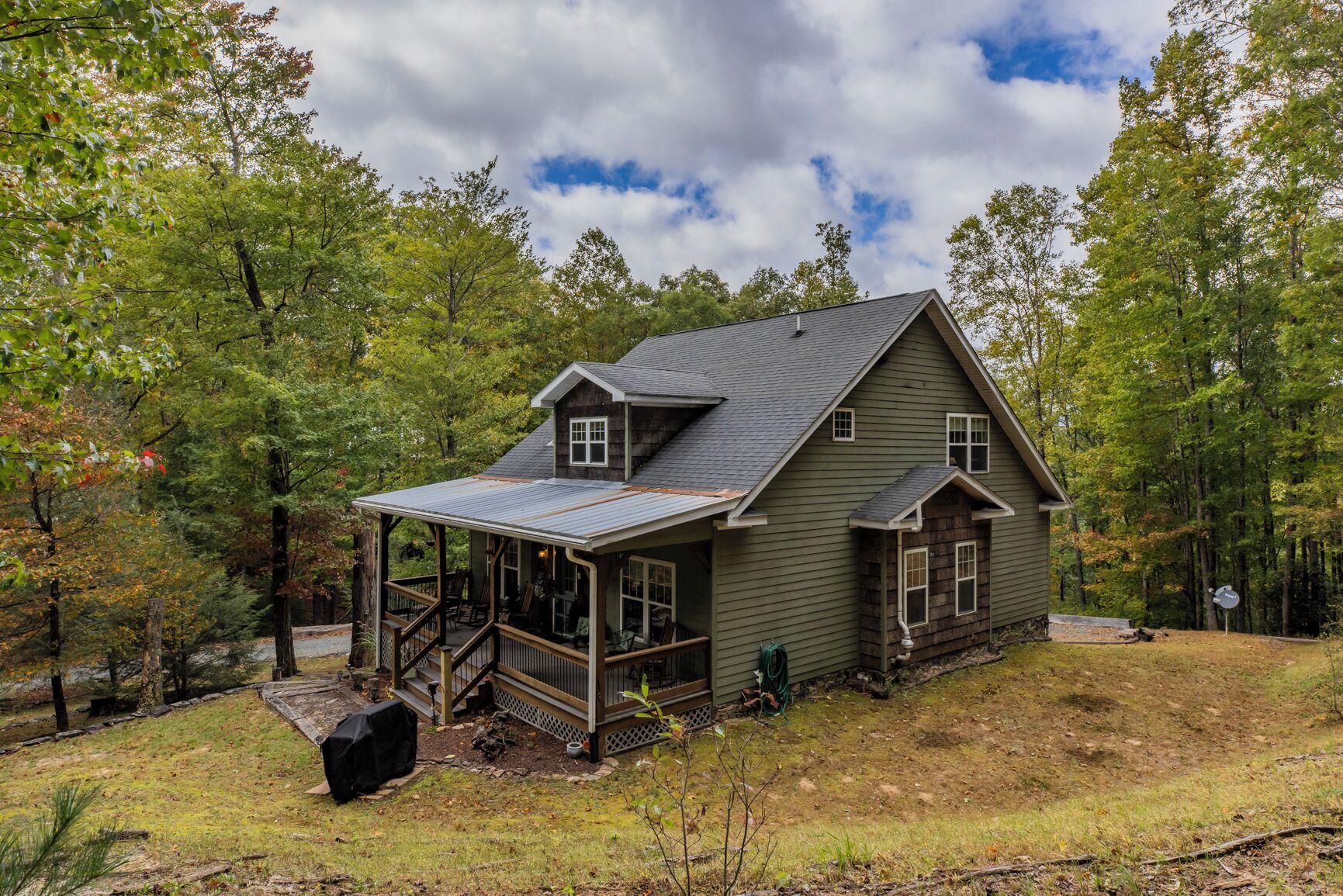 Une maison à deux étages avec un porche couvert et un petit abri attenant.