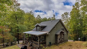 A two-story house with a covered porch and a small attached shed.