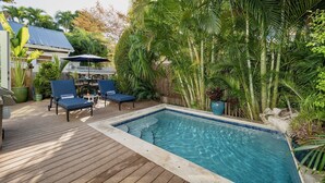 Une piscine rectangulaire dotée d’une terrasse en bois et de chaises longues.