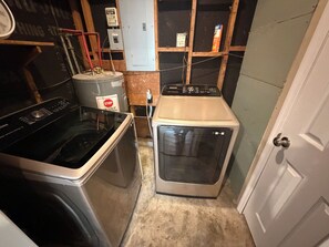 A compact laundry room with a washing machine, a dryer, and a water heater. - Cozy 4 bedroom House 2.5 bath (Albany)