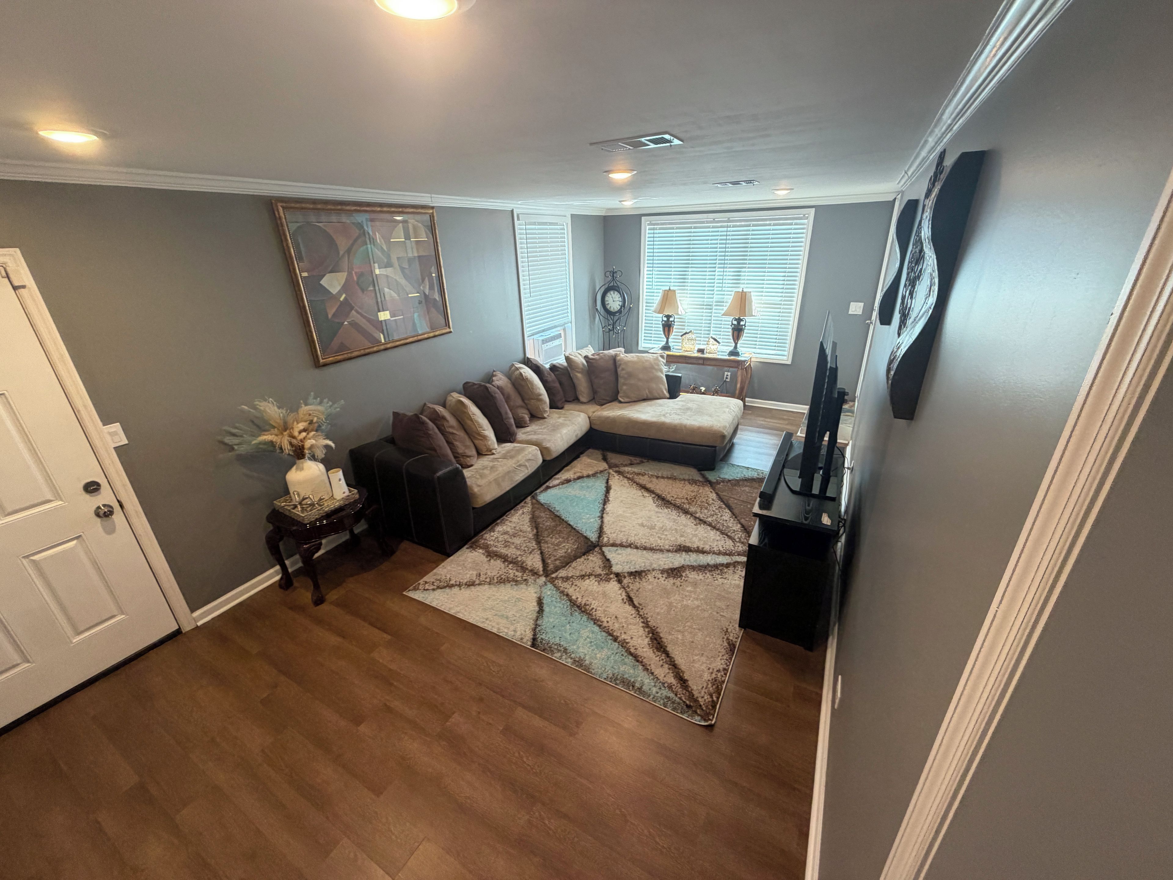 A living room with a sectional sofa, a flat-screen TV, and a decorative rug.