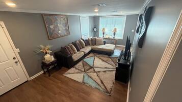 A living room with a sectional sofa, a flat-screen TV, and a decorative rug.