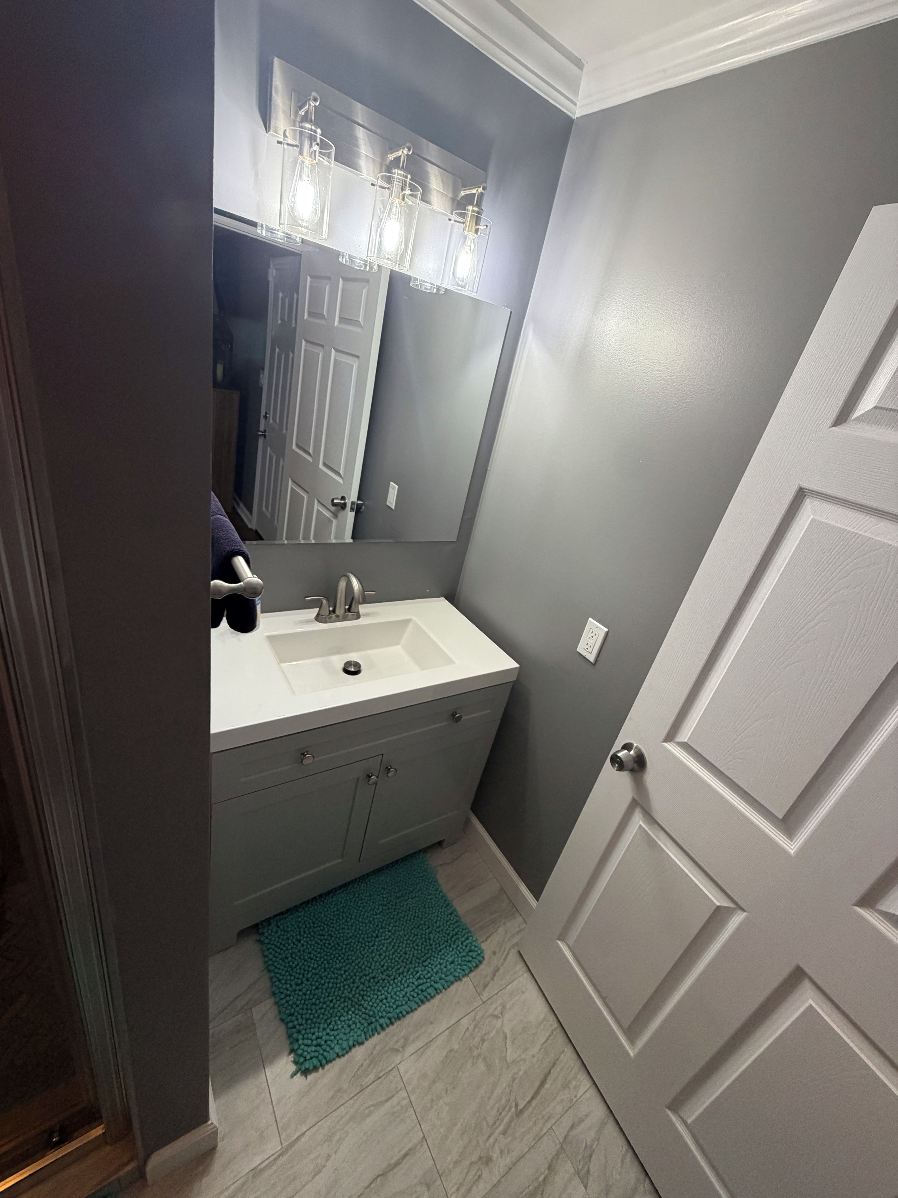 A bathroom with a white sink, a mirror, and a door.