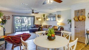 A spacious living room with a dining area, a ceiling fan, and a view to the outside. - Walk to Beach: PCB Condo w/ Oceanfront Pool Access (Panama City Beach)