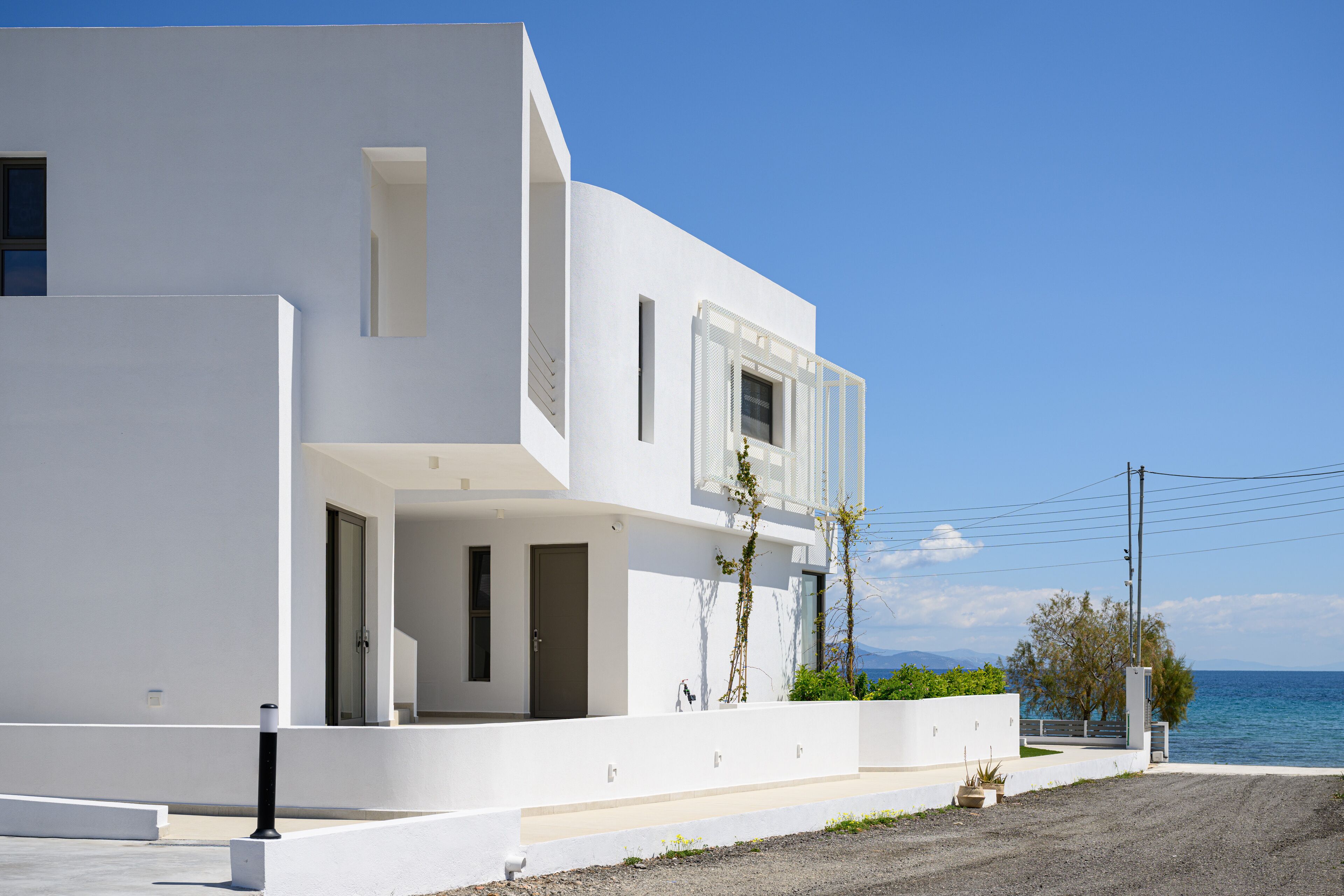 Um edifício moderno e branco com varanda e vista para a água.